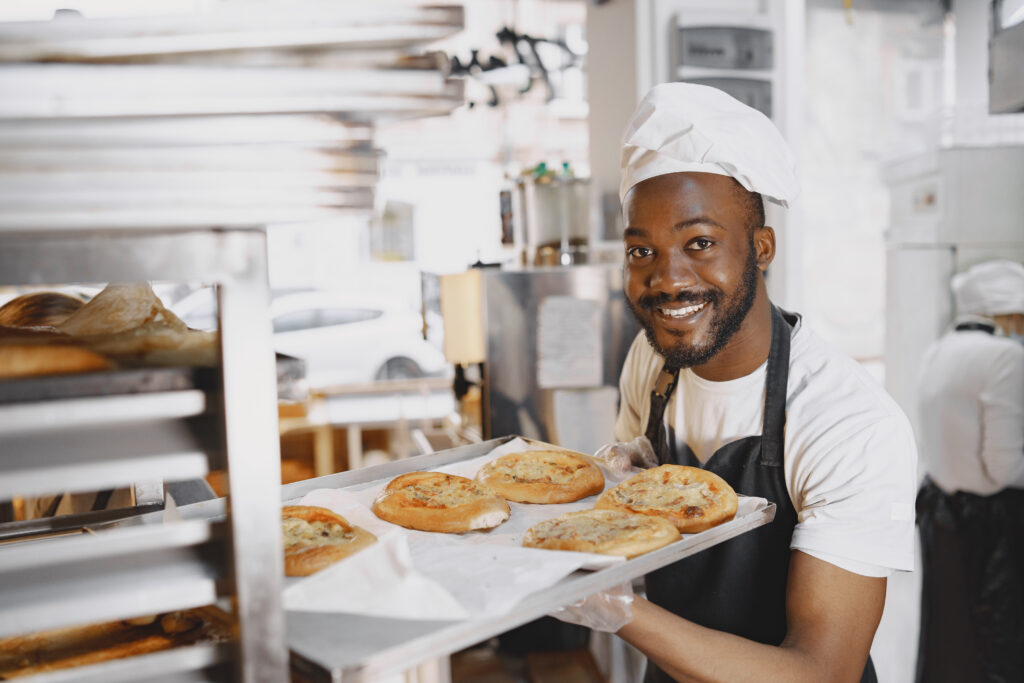 shot handsome baker putting trays fresh bread stand baking manufacture african american